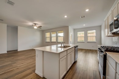 Kitchen featuring stainless steel appliances, a ceiling fan, light wood-style floors, open floor plan, and decorative backsplash