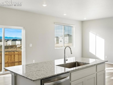 Kitchen featuring light wood finished floors, light stone countertops, white cabinetry, stainless steel dishwasher, and recessed lighting