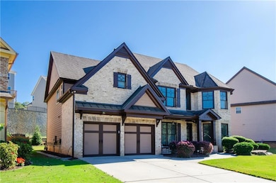 View of front facade with a front yard, brick siding, a garage, and driveway
