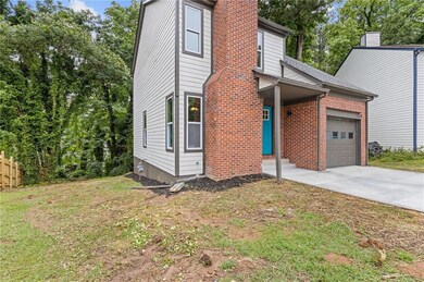 View of front of home with a chimney, an attached garage, concrete driveway, and brick siding