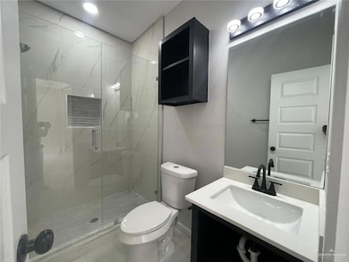 Full bath with vanity, a marble finish shower, baseboards, and toilet