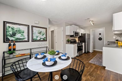 Dining area featuring dark hardwood / wood-style flooring, sink, rail lighting, and a textured ceiling