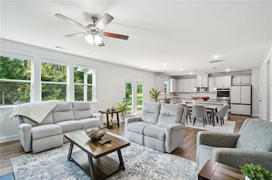 Living room with wood finished floors, recessed lighting, and a ceiling fan