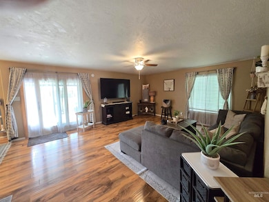 Living area featuring healthy amount of natural light, wood finished floors, ceiling fan, and a textured ceiling