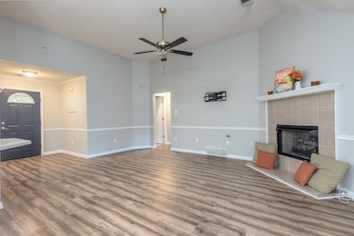 Unfurnished living room with dark wood-style flooring, a tile fireplace, ceiling fan, and high vaulted ceiling