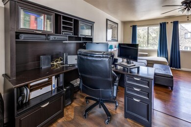 Home office featuring a ceiling fan and dark wood-style floors