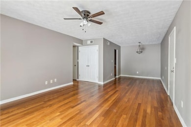 Empty room featuring a ceiling fan, wood finished floors, and a textured ceiling