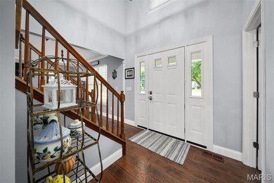 Entrance foyer with stairway, wood floors, and a high ceiling