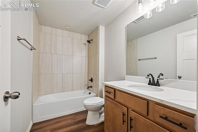 Bathroom featuring shower / bath combination, vanity, and dark wood-style floors