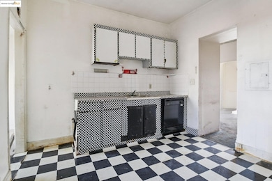 Kitchen featuring tile patterned floors, electric panel, dishwasher, and white cabinets