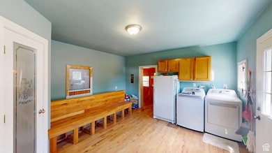 Laundry area with light wood-style flooring, plenty of natural light, cabinet space, and separate washer and dryer
