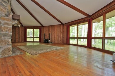 The circular living room features a wood beamed ceiling and full length windows.