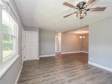 Unfurnished room featuring a textured ceiling, wood finished floors, a chandelier, and a ceiling fan