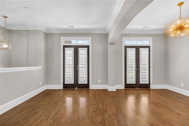 Entrance foyer featuring a chandelier, french doors, plenty of natural light, and ornamental molding