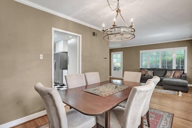 Dining room with a chandelier, wood finished floors, baseboards, and ornamental molding