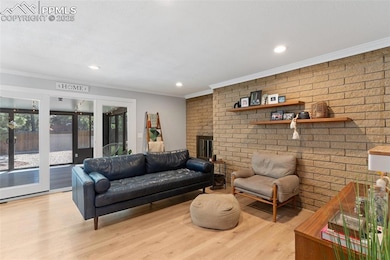 Spacious living area with decorative molding, brick fireplace, and modern recessed lighting