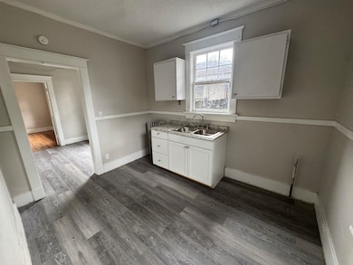 Kitchen with white cabinets, dark wood-style floors, a textured ceiling, and light countertops