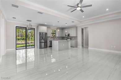 Kitchen with crown molding, open floor plan, a center island, stainless steel appliances, and gray cabinets