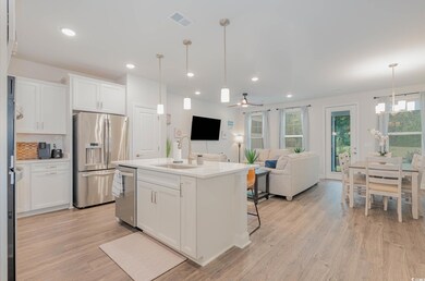 Kitchen featuring stainless steel appliances, light wood-type flooring, white cabinets, backsplash, and open floor plan