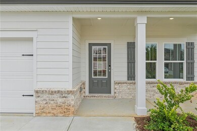 Property entrance featuring covered porch, brick siding, and a garage