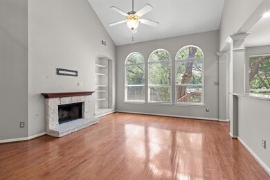 Unfurnished living room with built in features, healthy amount of natural light, a stone fireplace, high vaulted ceiling, and wood finished floors