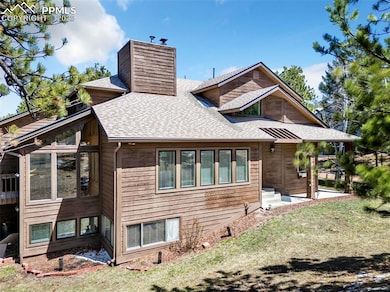 Rear view of house featuring a chimney, a sunroom, and roof with shingles