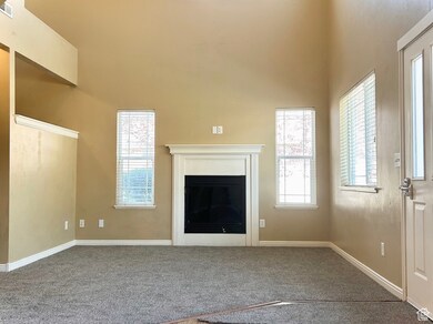 Unfurnished living room with carpet floors, a glass covered fireplace, and a high ceiling
