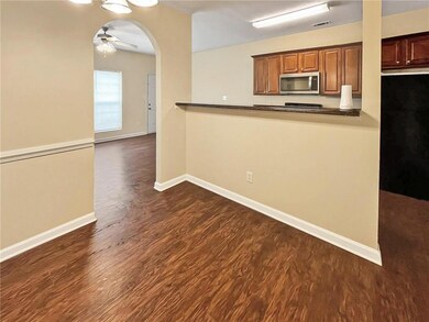 Kitchen featuring stainless steel microwave, dark wood-type flooring, dark countertops, and ceiling fan