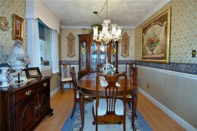 Impressive dining roof with laminate wood flooring, chair rail, molding, chandelier and custom draperies.