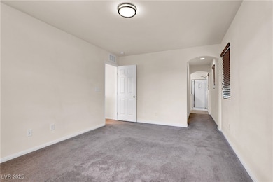 Spare room featuring arched walkways and carpet fl
