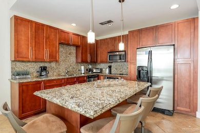 Kitchen featuring stainless steel appliances, light stone countertops, visible vents, and a kitchen bar