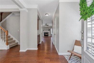 Foyer entrance featuring dark wood finished floors, stairs, a glass covered fireplace, ceiling fan, and crown molding