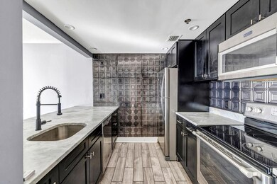 Kitchen featuring sink, light stone countertops, appliances with stainless steel finishes, light hardwood / wood-style floors, and tasteful backsplash