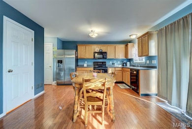 Kitchen with black appliances, light wood-style flooring, light countertops, and light brown cabinets