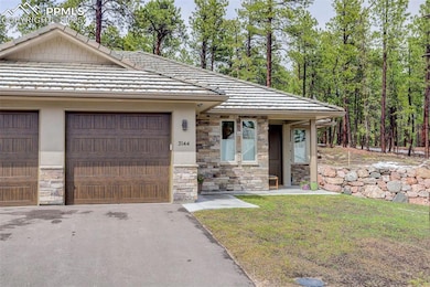 View of front facade featuring stone siding, a tile roof, driveway, and stucco siding