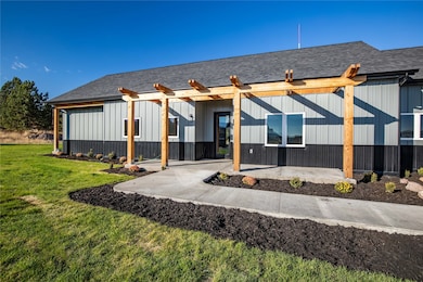 Rear view of property featuring roof with shingles, a porch, a yard, and board and batten siding