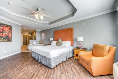 Bedroom featuring ceiling fan, ornamental molding, hardwood / wood-style floors, and a tray ceiling