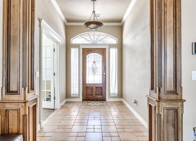 Foyer with light tile flooring and crown molding
