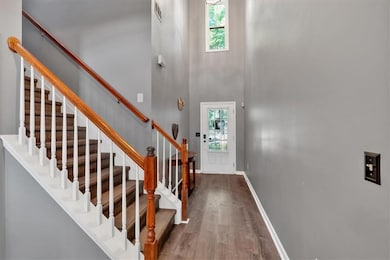 Entrance foyer featuring wood finished floors, stairway, and a high ceiling