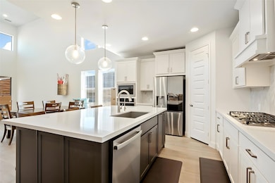 Kitchen with appliances with stainless steel finishes, white cabinetry, decorative light fixtures, recessed lighting, and backsplash