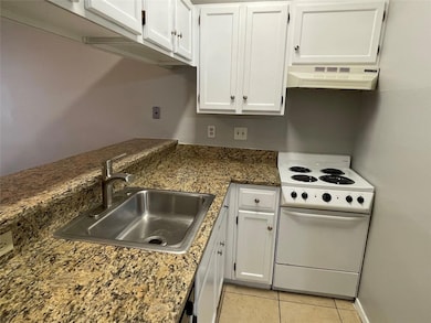 Kitchen featuring white electric range oven, white cabinetry, light tile patterned floors, and exhaust hood