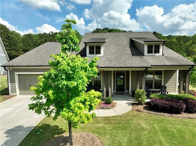 Craftsman-style home featuring a porch, driveway, roof with shingles, a front yard, and a garage