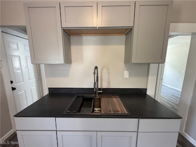Kitchen featuring dark wood-type flooring, dark countertops, and white cabinets