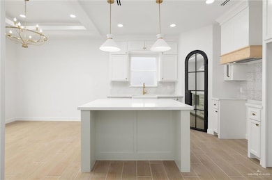 Kitchen featuring white cabinets, a kitchen island, and custom exhaust hood