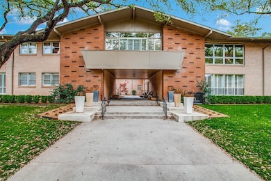View of front of house with brick siding, a front yard, and a balcony