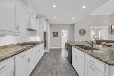 Kitchen with a sink, stone countertops, white cabi