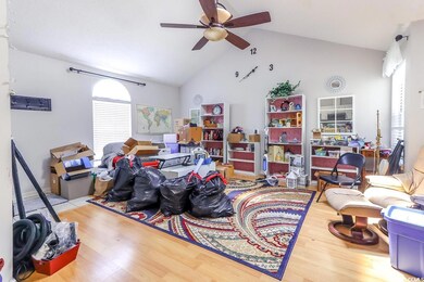 Living area with a ceiling fan, wood finished floors, and high vaulted ceiling