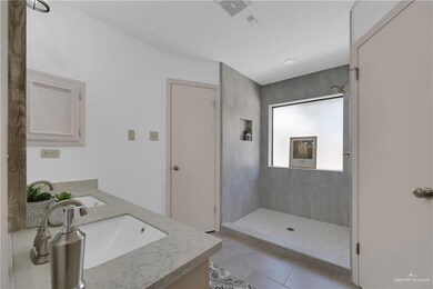 Full bathroom with double vanity, visible vents, tile patterned flooring, a walk in shower, and a sink
