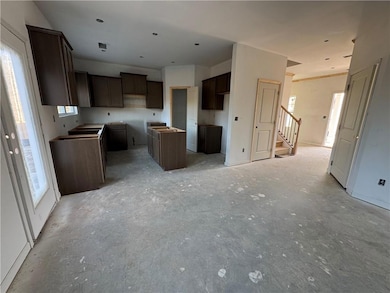 Kitchen with plenty of natural light, a center island, unfinished concrete floors, and dark brown cabinetry