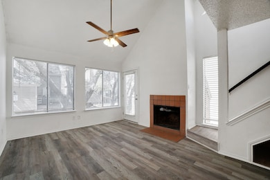 Unfurnished living room with a tile fireplace, ceiling fan, dark hardwood / wood-style flooring, and high vaulted ceiling